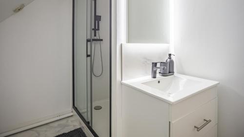une salle de bain blanche avec un lavabo et une douche dans l'établissement Secret de la Monnaie - Duplex - 2 Personnes - Rue Historique de Troyes, à Troyes