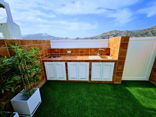 een badkamer met een wastafel en een aanrecht met groen gras bij Residence Puerto Rico in Puerto Rico de Gran Canaria