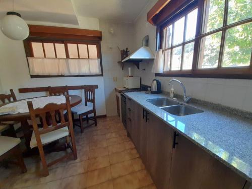 uma cozinha com um lavatório e uma mesa de jantar em La Casa de la Isla em San Martín de los Andes