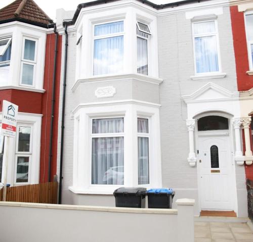 a white house with two trash cans in front of it at Cricklewood Deluxe Ensuite Room in London