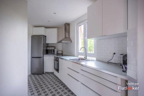 La cuisine blanche est équipée d'un évier et d'un réfrigérateur. dans l'établissement Quiet cosy and large apartment with Terrace Top location, à Saint-Ouen