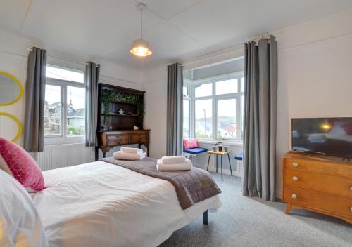a bedroom with a bed and a tv and windows at Fourwinds in Towyn