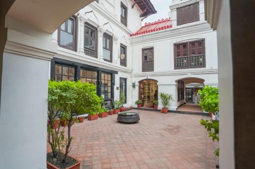 a courtyard in a white building with potted plants at Samsara Apartments by Baber Mahal Revisited in Kathmandu