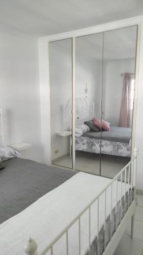 a white bedroom with a mirror and a bed at CASA GUELDE in Tías