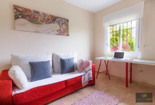 a red couch in a room with a table and a window at Las 7 parras in El Puerto de Santa María