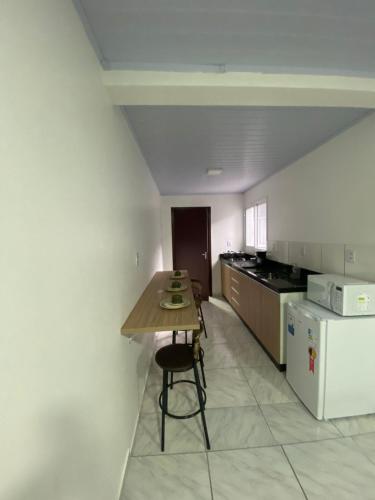 a small kitchen with a table and a refrigerator at Pousada Route 58 in Gravataí