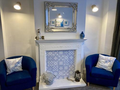 a fireplace with two blue chairs and a mirror at Fairfax in Southend-on-Sea