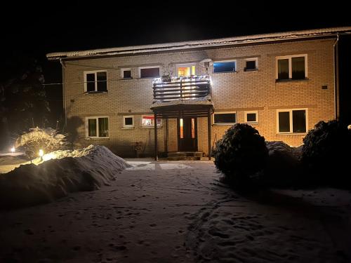 a building at night with snow in front of it at Valgemaja Majutus 