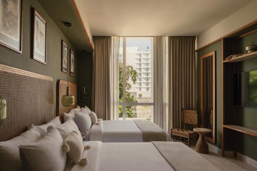 a hotel room with two beds and a window at Hotel Sureño Yucatan in Mérida