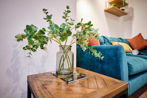 a vase on a table in front of a blue couch at Portstewart Central Loft Apartment in Portstewart
