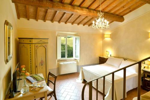a bedroom with a bed and a table and a chandelier at Locanda Le Giunche in Guardistallo