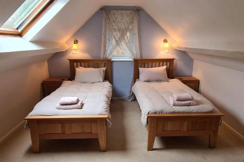 two twin beds in a room with a window at Holiday Cottage in Snowdonia (Sleeps 10) in Harlech