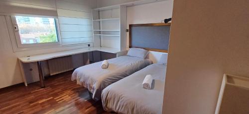 um quarto de hotel com duas camas e uma janela em MAGNÍFICA RESIDENCIA em El Masnou