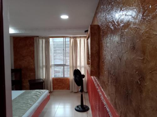 een slaapkamer met een bed en een muur met een raam bij Hotel el playon in Medellín