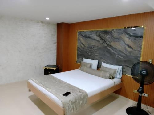 een slaapkamer met een wit bed en een schilderij aan de muur bij Hotel el playon in Medellín
