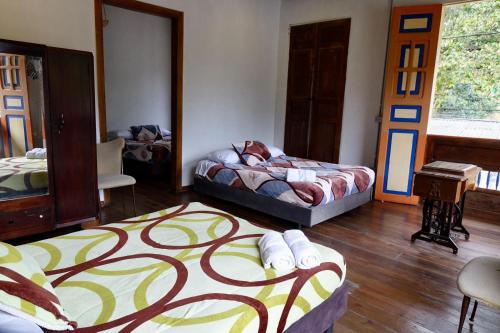 a bedroom with two beds and a table and chairs at HOSTAL CASA VICTORIA PIJAO in Pijao