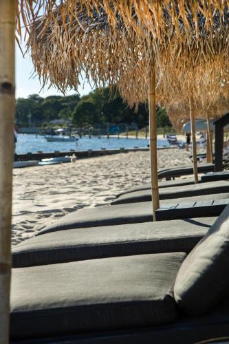 a row of lounge chairs with straw umbrellas on a beach at Aqua by American Beech - Adults Only in Aquebogue