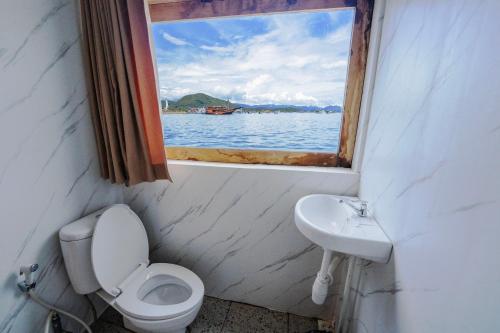 a bathroom with a toilet and a sink with a window at Phinisi Boat Maheswari Komodo in Labuan Bajo