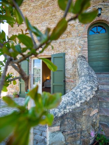 a stone house with green doors and a window at Locanda Le Giunche in Guardistallo