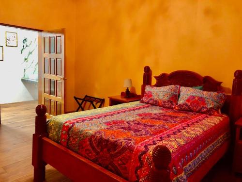 Schlafzimmer mit einem Bett mit einer roten Bettdecke in der Unterkunft Banyan Rose Room 4 in Orange Walk Town