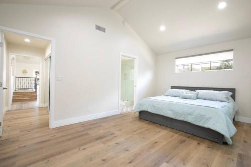 a white bedroom with a bed and a large window at Beautiful Spacious Home in Los Angeles