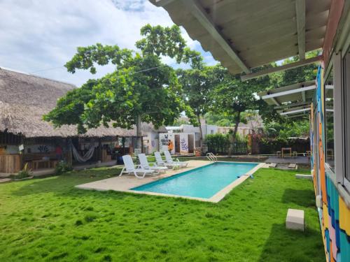 a backyard with a swimming pool with chairs and trees at Green Belly Surf Hostel in El Paredón Buena Vista