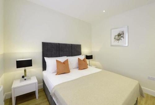 a bedroom with a large white bed with orange pillows at Bond Street Mayfair Penthouse Sleeps up to 6 in London