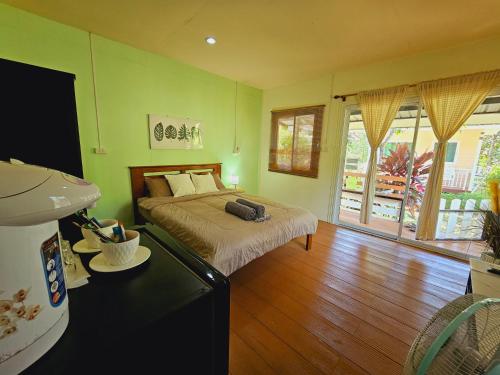 a bedroom with a bed in a room with green walls at Baan suan khun ta บ้านพักสวนคุณตา in Ko Chang