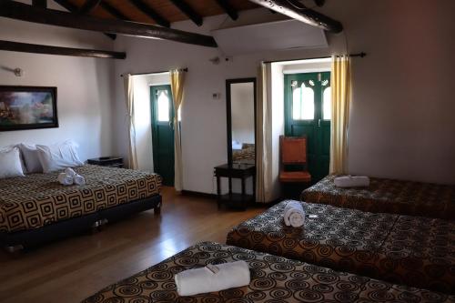 a hotel room with two beds and a mirror at Mongui Plaza Hotel in Monguí