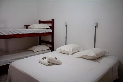 two bunk beds with white sheets and pillows on them at Pousada Yurgs in Caraguatatuba