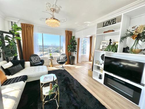 a living room with a white couch and a large tv at Amazing Ocean View Top Floor Sleeps 4 in Long Beach