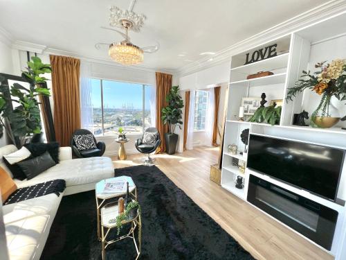 a living room with a white couch and a large tv at Your Penthouse Ocean view with City lights and Queen Mary too in Long Beach