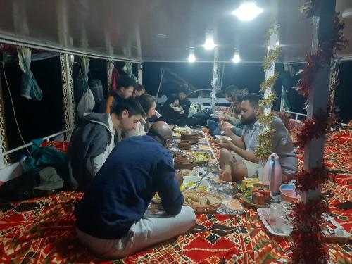 un grupo de personas sentadas alrededor de una larga mesa comiendo comida en Dream of life, en Naj‘ al ‘Amrāb