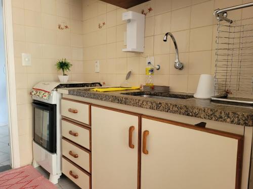 a kitchen with a sink and a stove top oven at Maravilhoso apto à beira-mar in Caraguatatuba