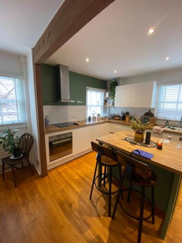 Modern 1BD Farmhouse-Style Flat - Dalston! في لندن: مطبخ مع طاولة خشبية وبعض الكراسي