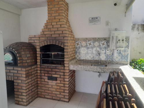 um forno de tijolo numa cozinha com um lavatório em Apartamento flat em condomínio club em Aracaju