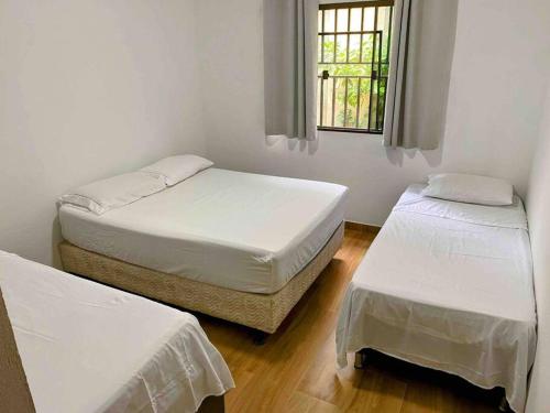 2 camas individuales en una habitación con ventana en Aconchegante casa perto da praia, en Fundão