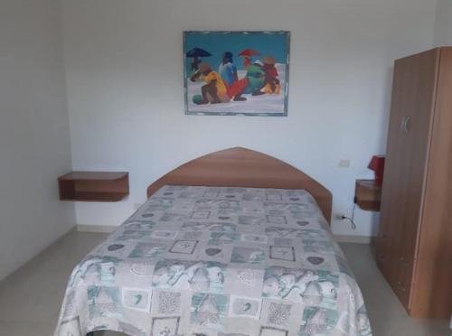 un letto in una camera da letto con un dipinto sul muro di Perla Marina a San Nicola