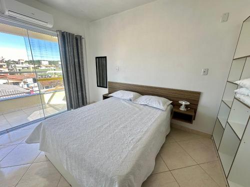 Un dormitorio con una cama y una ventana grande. en Res. Dona Olímpia, en Bombinhas