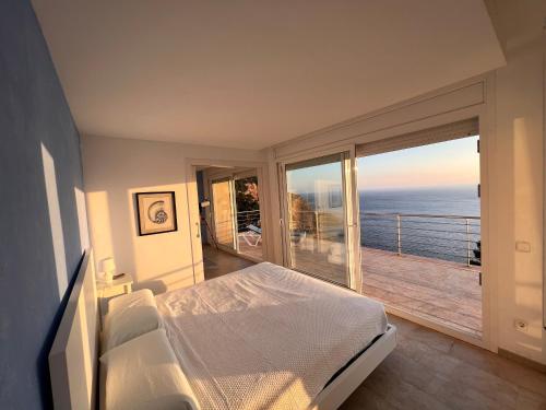 a bedroom with a bed and a balcony with the ocean at Villa Sa Calma in Begur