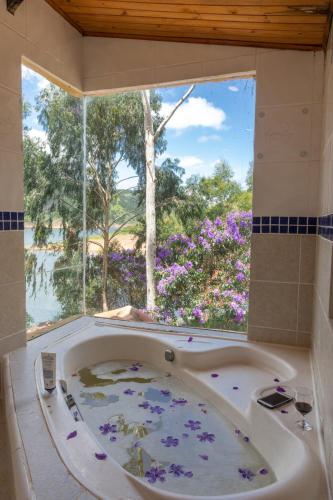 a bath tub in front of a window with flowers at Casa INTI Refugio Romantico Pague duas noites minimo e a terceira e brinde, menos feriados in Natividade da Serra