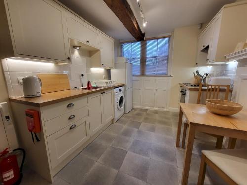 une cuisine avec des placards blancs et une table dans l'établissement York Minster View, à York