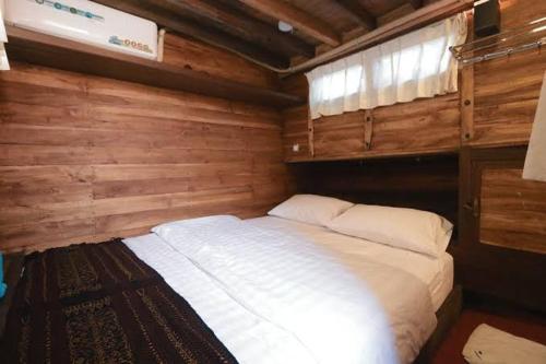 a large white bed in a room with wooden walls at Phinisi Floresta Komodo in Labuan Bajo