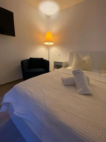 a large white bed with a lamp and a chair at Apartments in der Rostocker Innenstadt in Rostock