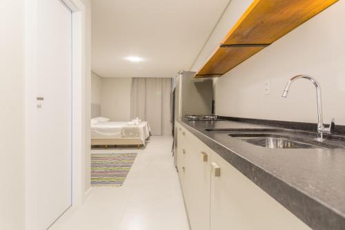 uma cozinha com um lavatório e uma cama num quarto em Studio Itapema a 230m da Passarela na Barra WV4437 em Balneário Camboriú