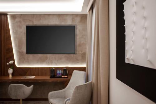 um quarto com duas cadeiras e uma televisão na parede em Hotel Via Veneto em Roma