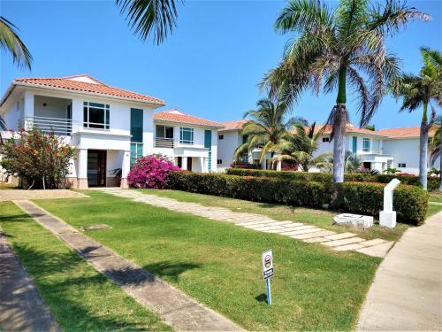 a house with palm trees and a sign in the grass at Villla en la playa Cartagena 5 in Cartagena de Indias