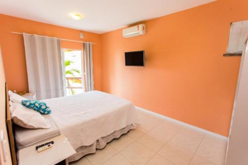 a bedroom with orange walls and a bed and a tv at Panorama Cumbuco in Cumbuco