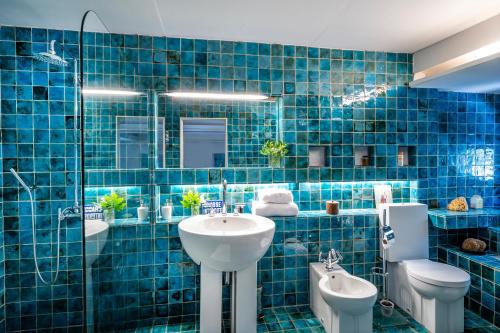 La salle de bains est pourvue de carrelage bleu, d'un lavabo et de toilettes. dans l'établissement Domaine de Valloncourt, à Cheval-Blanc