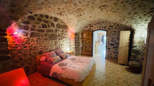 Un dormitorio con una cama en una pared de piedra. en Gîte des 3 vallées - Le soleil des Cévennes, en Saint-Jean-du-Gard